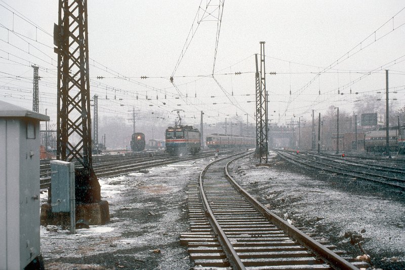 19820547-amtk.jpg - An Amtrak RS3 switcher, AEM-7 #938 and a ConnDOT/Conrail commuter train from Grand Central Terminal at the west approaches to New Haven station during a snow squal. December 23, 1982.